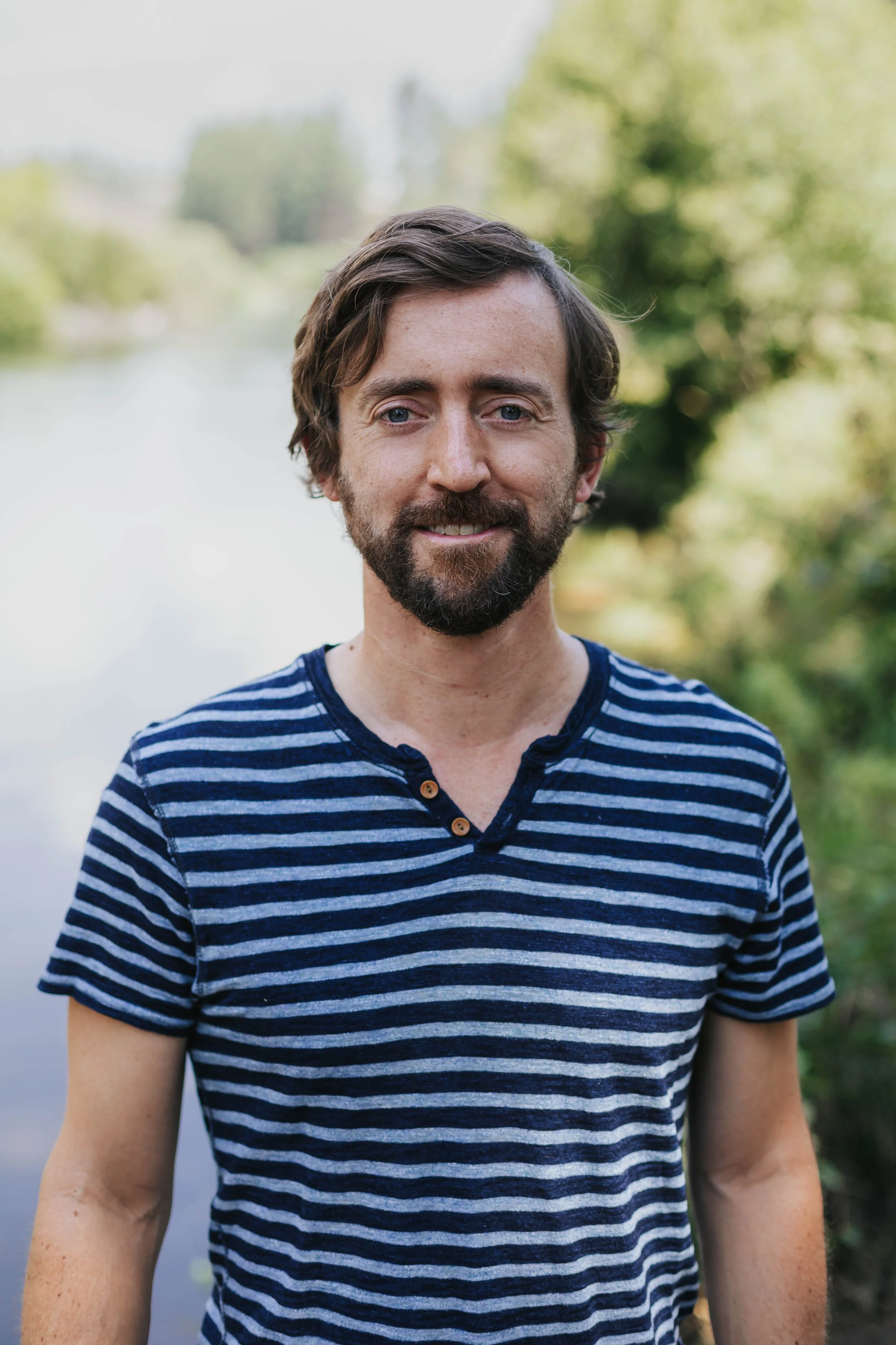 Benjamin Bryan, LMT, standing outdoors along a river in Bend, Oregon