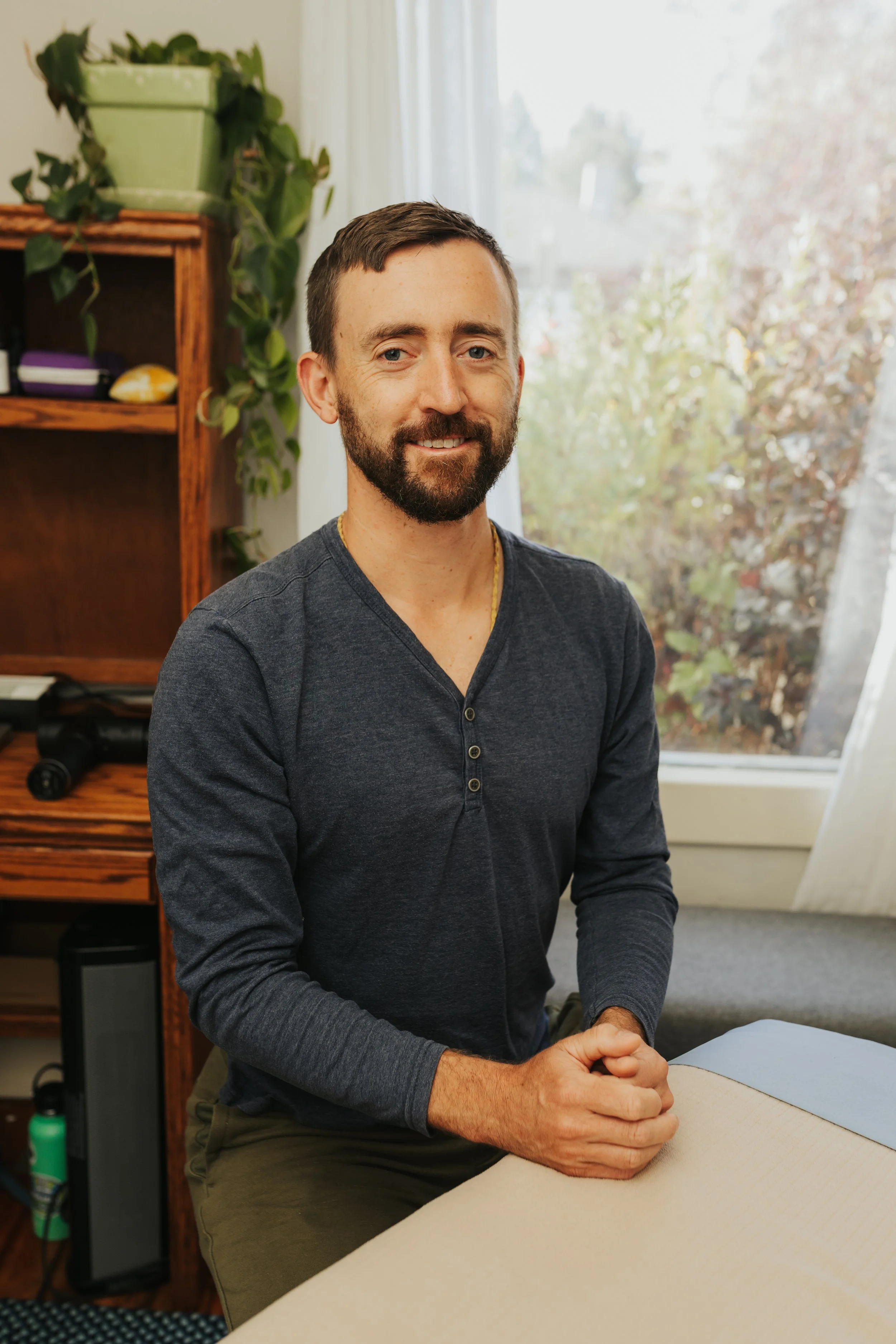 Benjamin Bryan, LMT, seated beside the treatment table in his Bend, Oregon studio